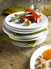Stapeln von weißen Tellern, einige mit gesunden Knabbereien, Gemüse, Oliven und Nüssen — Stockfoto