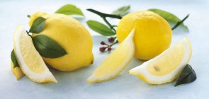 Cuñas de limón y hojas de limón - foto de stock