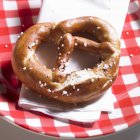 Lye pretzel on a plaid plate — Stock Photo
