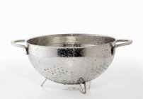 Closeup view of a wet dripping colander on white surface — Stock Photo