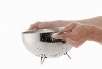 Cropped view of hands holding a dripping colander — Stock Photo