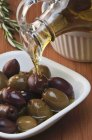 Оливковое масло, разливающееся по смешанным оливкам — стоковое фото