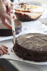 Closeup vista cortada de pessoa espalhando esmalte de chocolate no bolo com faca — Fotografia de Stock