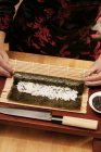 Woman rolling rice in nori sheet — Stock Photo