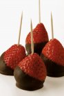 Chocolate-coated strawberries on toothpicks — Stock Photo