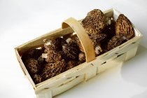 Elevated view of Morels in chip basket on white surface — Stock Photo