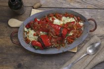 Peperoni rossi ripieni su piatto grigio su superficie di legno — Foto stock