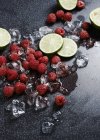 Raspberries and limes with ice cubes — Stock Photo