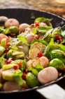 Жареная брюссельская капуста с базиликом, луком и семенами граната на сковороде — стоковое фото