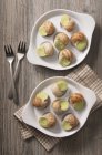 Vue du dessus des escargots de Bourgogne préparés avec beurre aux herbes sur assiettes — Photo de stock