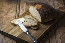 Pão fatiado com manteiga e faca — Fotografia de Stock