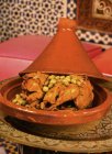 Куриный таджин с зелеными оливками в коричневой миске за столом — стоковое фото