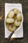 Cebollas asadas marinadas en plato blanco con tenedor - foto de stock