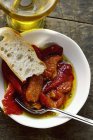Peperonata - pimientos rojos marinados en aceite sobre plato blanco con tenedor - foto de stock