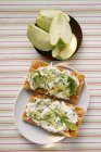 Crispbreads with quark and rocket; fresh apple wedges  on white plate and on black one — Stock Photo