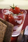 Кварк і помідор з хрустким хлібом у склянці над червоною поверхнею — стокове фото