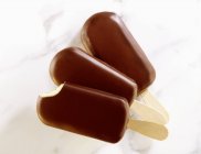 Vue rapprochée de crème glacée vanille enrobée de chocolat sur bâtons — Photo de stock