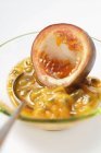 Spooning out passion fruit flesh — Stock Photo
