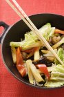Ingredientes para plato de verduras asiáticas en wok sobre la superficie roja - foto de stock