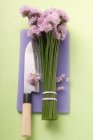 Chive flowers and knife on purple chopping board — Stock Photo
