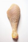Vue rapprochée d'une jambe de poularde crue sur une surface blanche — Photo de stock
