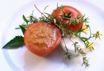 Molho de tomate em tomate oco; ervas frescas na placa branca — Fotografia de Stock