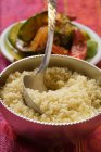 Couscous in ciotola d'argento, piatto di verdure dietro sulla superficie rossa — Foto stock