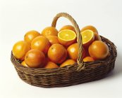 Апельсины в мелкой плетеной корзине — стоковое фото