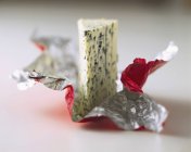 A piece of Roquefort on plastic packaging on white surface — Stock Photo