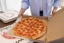 Человек держит коробку пиццы — стоковое фото