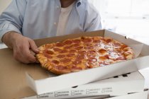 Человек берет кусок пиццы — стоковое фото