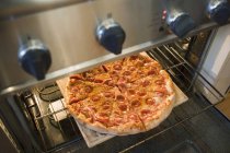 Pizza de pepperoni en el horno - foto de stock