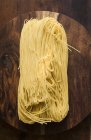 Top view of egg noodles on wooden plate — Stock Photo