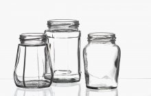 Três frascos de conservação vazios em uma folha de vidro — Fotografia de Stock