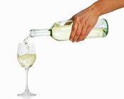 Mão feminina derramando vinho branco — Fotografia de Stock
