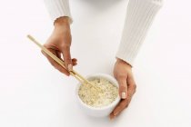 Womans holding chopsticks in bowl of rice — Stock Photo