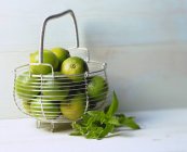 Several limes in wire basket — Stock Photo
