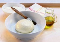 Closeup view of yeast dough with brush in white bowl — Stock Photo