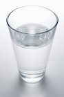 Glass of water on gray table — Stock Photo