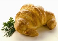 Croissant recién horneado con vegetación - foto de stock