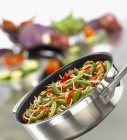 Жареные овощи в сковороде на размытом фоне — стоковое фото