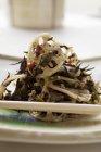 Salada de algas marinhas com raízes de lótus e gergelim na placa branca — Fotografia de Stock