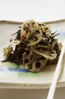 Салат з морськими водоростями з корінням лотоса і кунжутом на тарілці — стокове фото