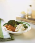 Варёные овощи в белой тарелке на белой поверхности — стоковое фото