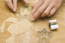 Closeup cropped view of hands cutting out star-shaped biscuit dough — Stock Photo
