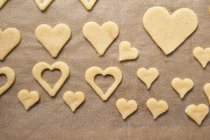 Top view of cut-out heart-shaped biscuits on baking parchment — Stock Photo