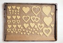 Vista superior de galletas cortadas en forma de corazón en bandeja para hornear - foto de stock