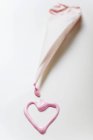 Closeup view of pink heart in glace icing and a piping bag — Stock Photo