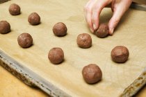 Vue recadrée de boules de pâte à noisettes disposées à la main sur une plaque à pâtisserie — Photo de stock