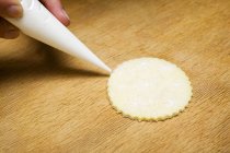 Closeup view of round biscuit with piping bag — Stock Photo